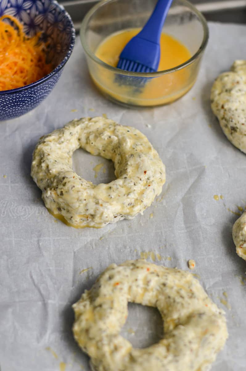 Brushing egg wash on greek yogurt bagels.