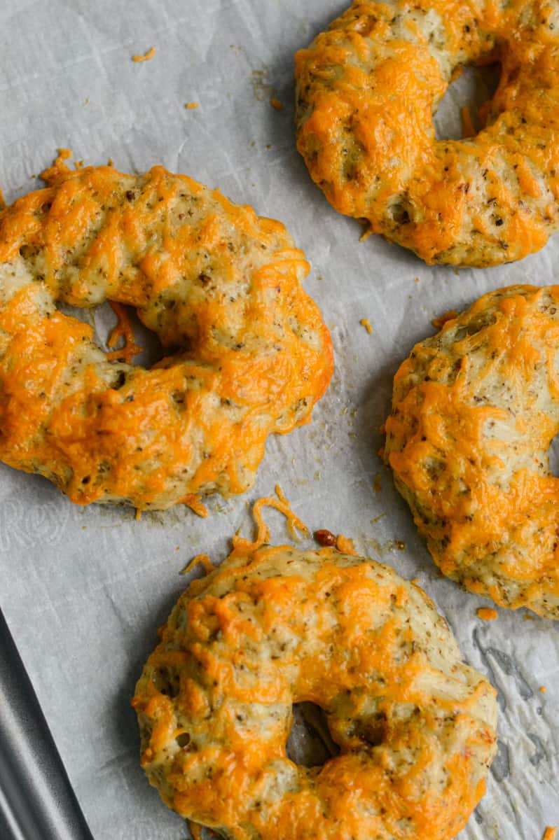Topping greek yogurt bagels with cheddar cheese and baking.