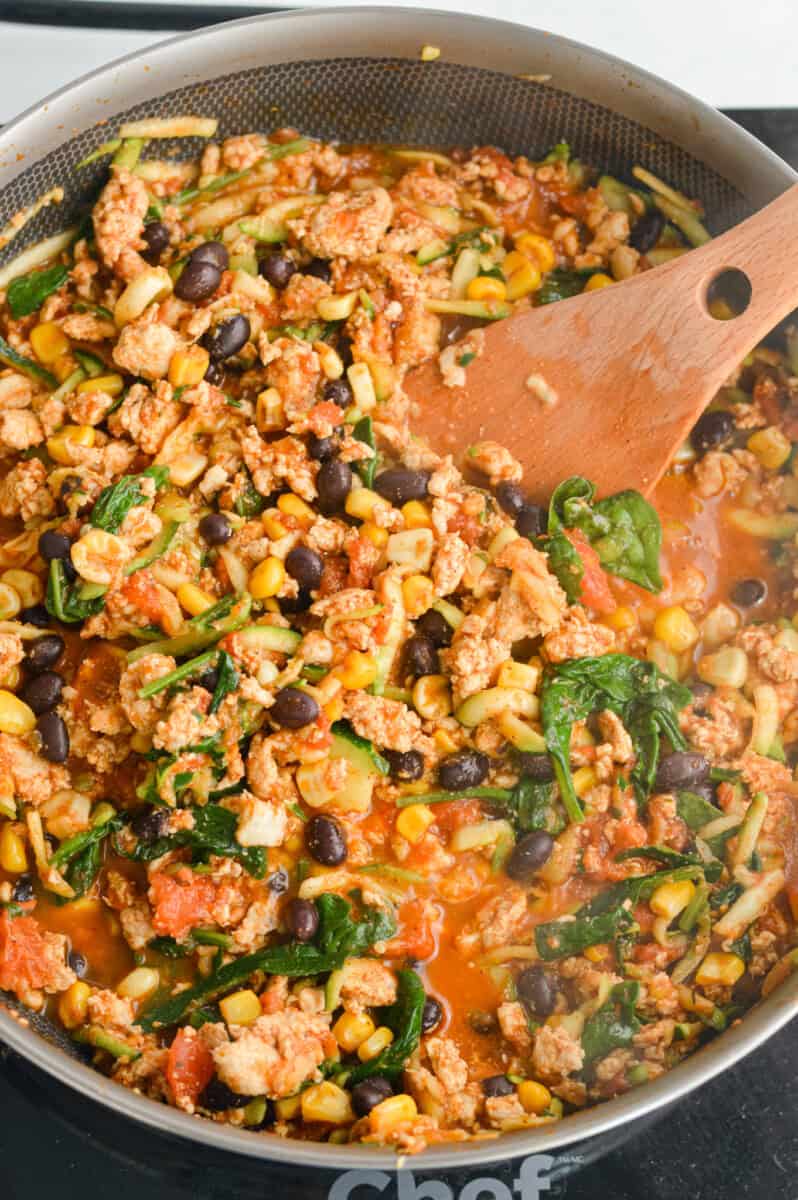 Mixing veggies, black beans and corn with ground turkey.