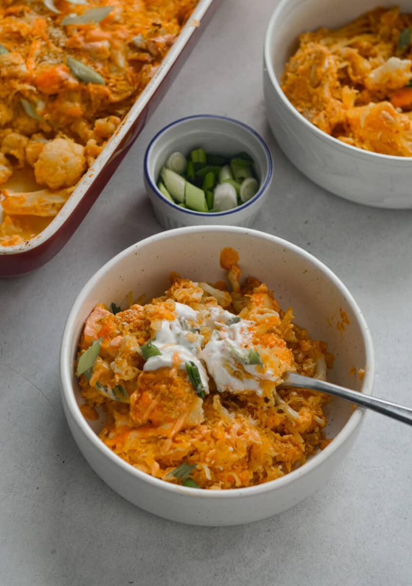 Bowl of spaghetti squash casserole topped with greek yogurt and green onion.