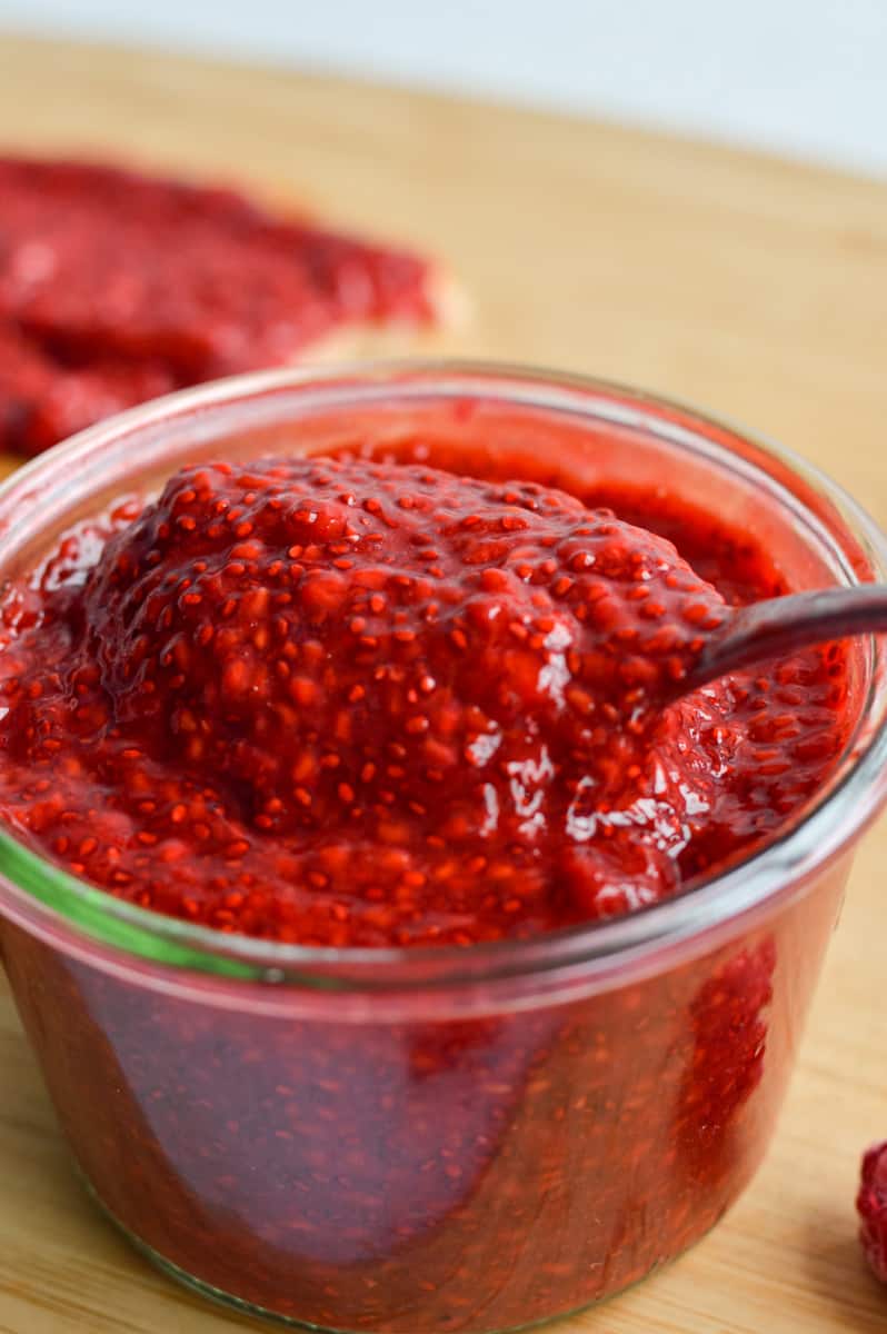 Jar of raspberry chia jam with a spoon.