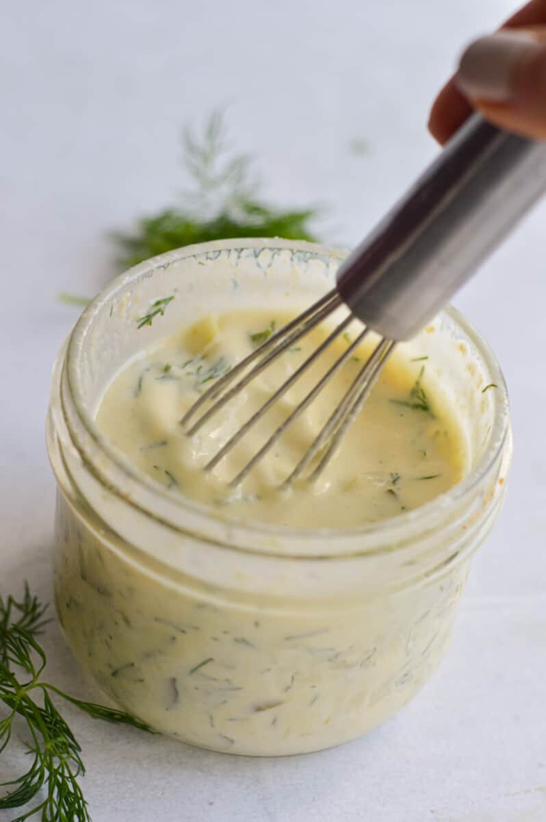 Mixing dill pickle salad dressing with a whisk.