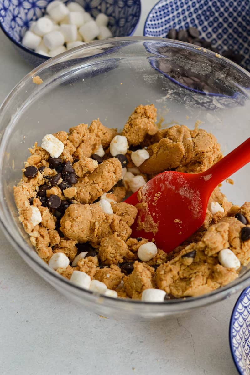 Mixing marshmallows, chocolate chips and graham crackers into dough.