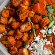 Buffalo tofu in a bowl with veggies and feta.