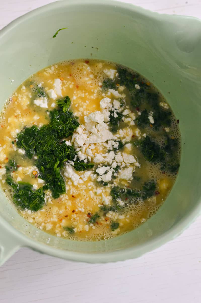 Adding spinach, feta and spices to beaten eggs.