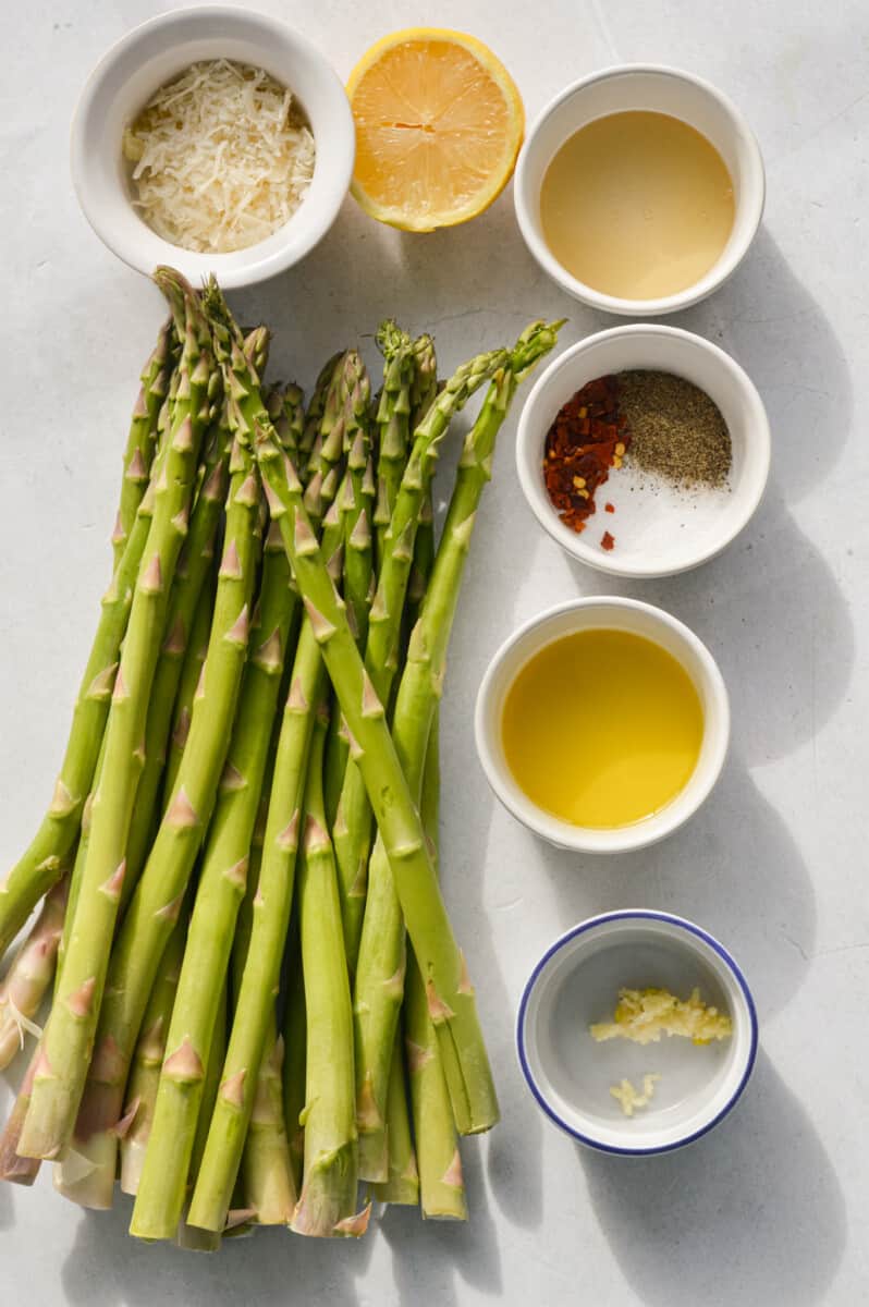 Ingredients including asparagus, lemon, olive oil, spices, honey and parmesan.