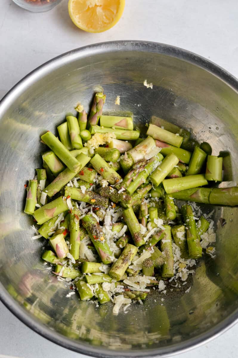 Mixing asparagus with olive oil, lemon, honey, spices and parmesan.