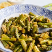 Blue plate with spicy parmesan air fryer asparagus.