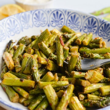 Blue plate with spicy parmesan air fryer asparagus.