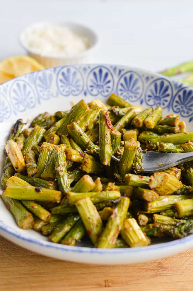 Blue plate with spicy parmesan air fryer asparagus.
