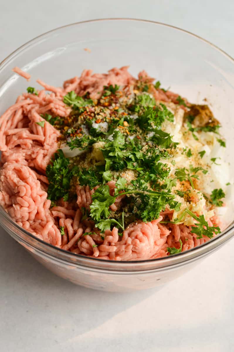 Adding meatball ingredients to a bowl.