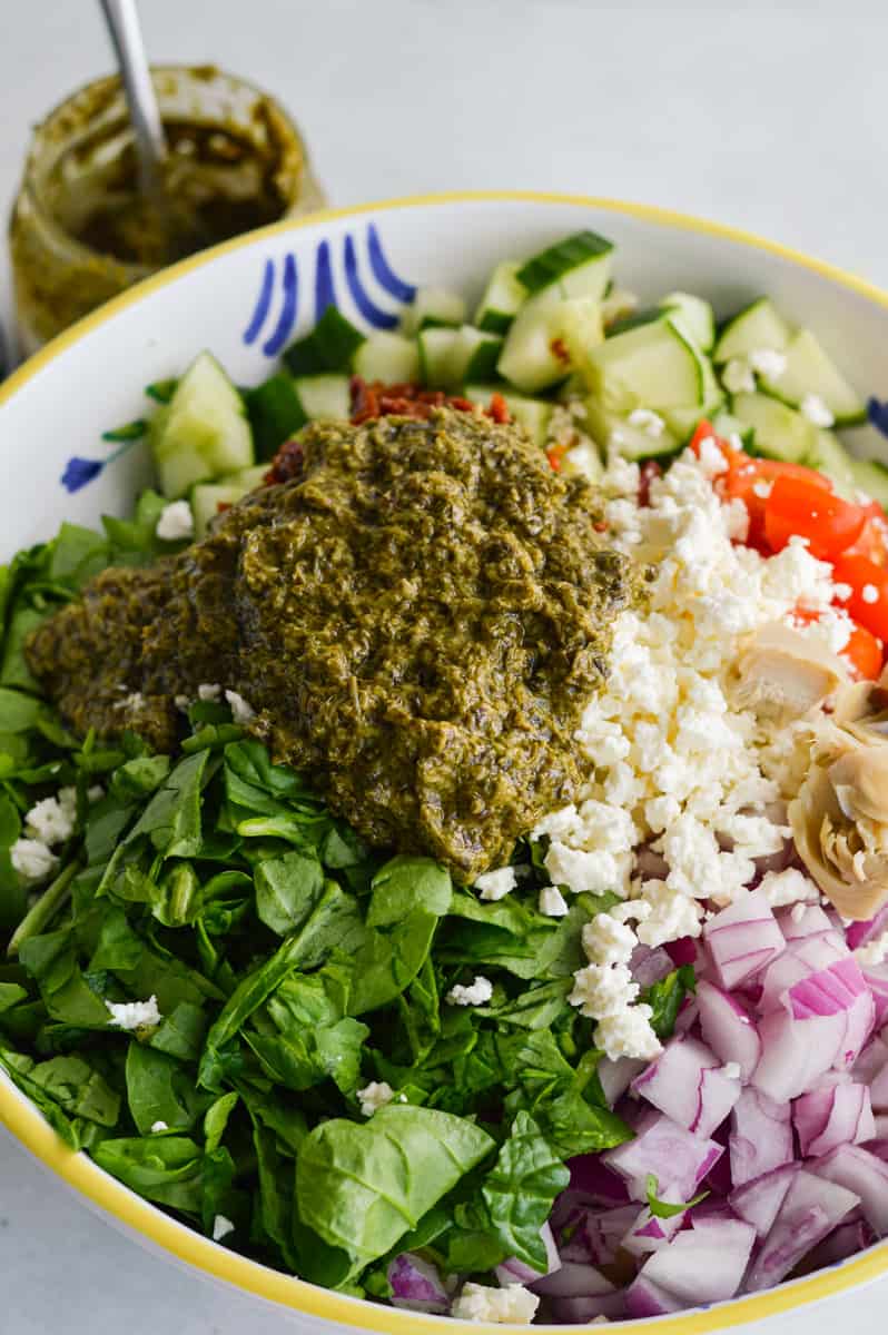 Adding pesto to pasta salad.