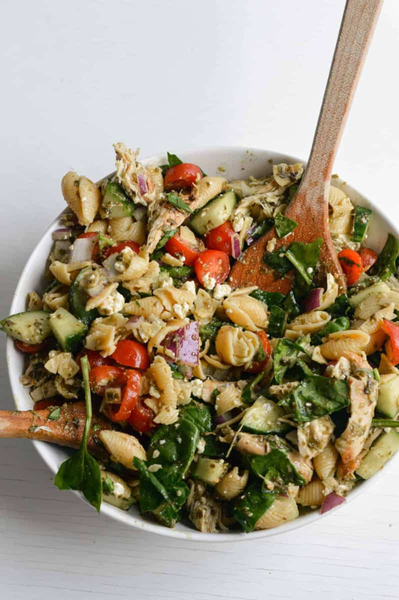 Bowl of chicken pesto pasta salad being mixed.