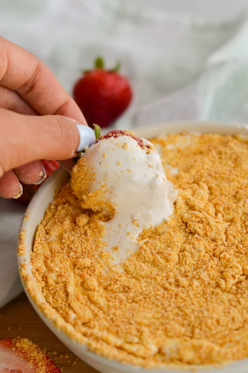 Dipping a strawberry in high protein fruit cheesecake dip.