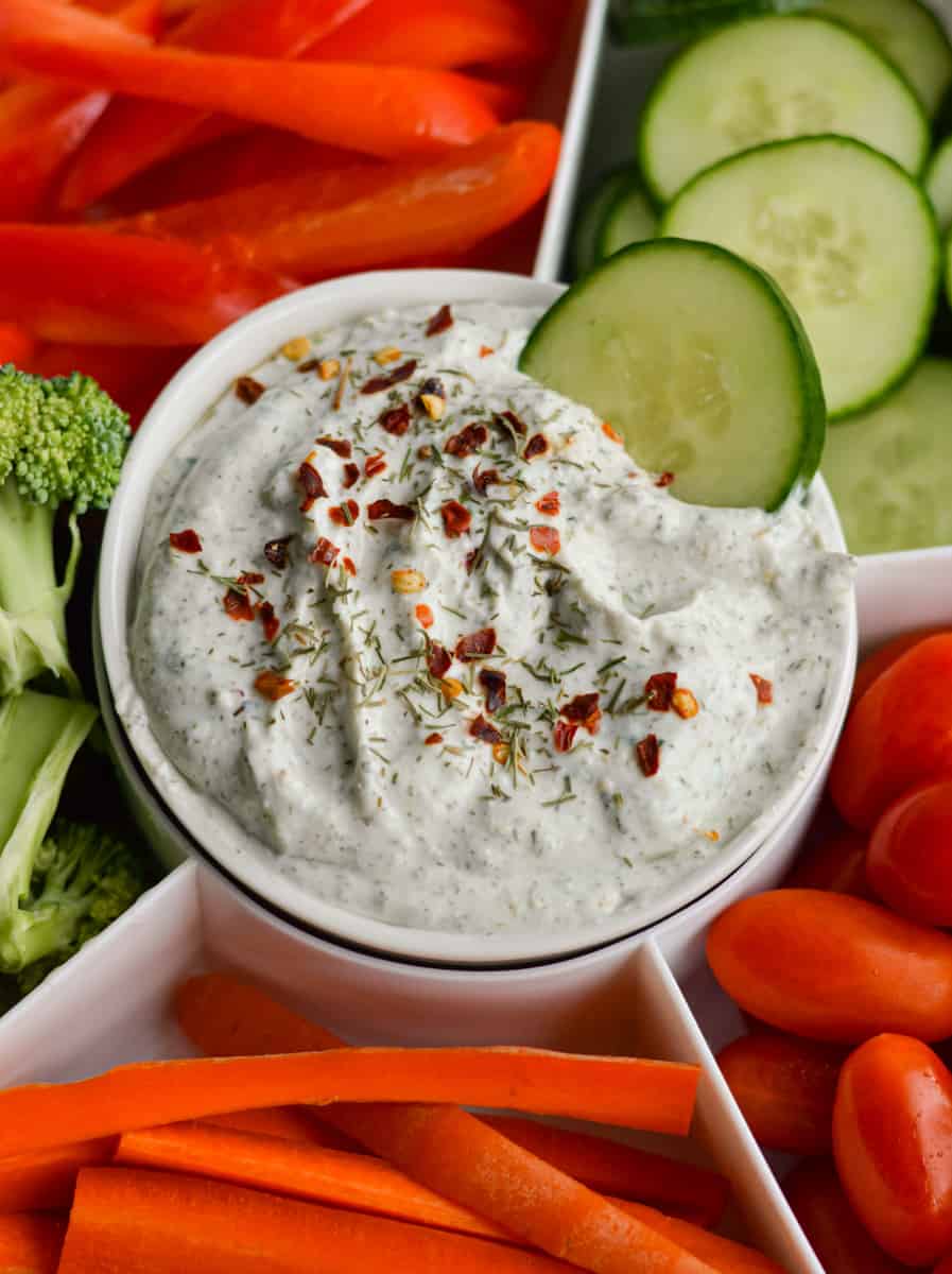 Dunking a cucumber into herb and garlic cottage cheese dip.