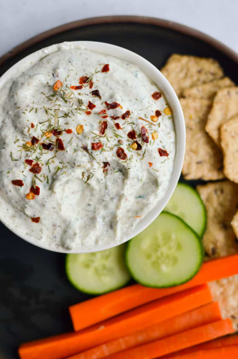 Serving cottage cheese dip with crackers, cucumbers and carrots.