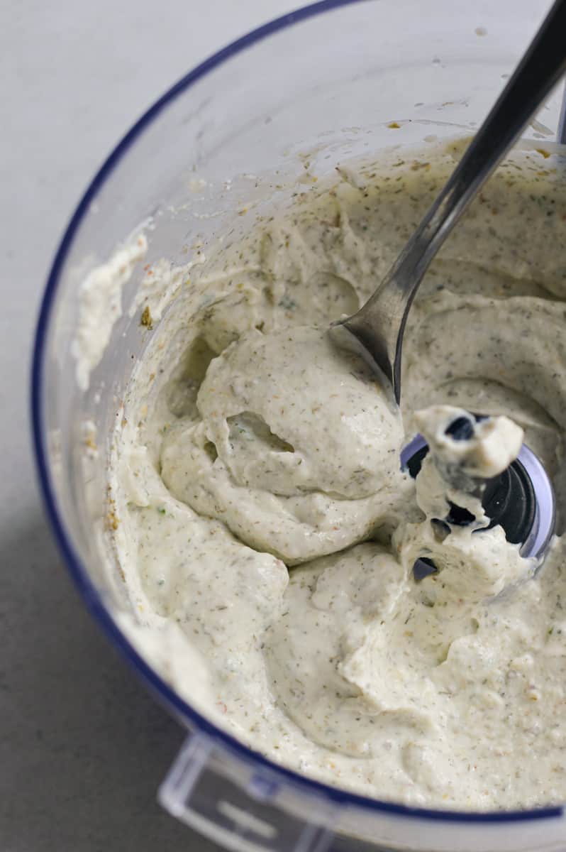 Cottage cheese dip being spooned out of a food processor.