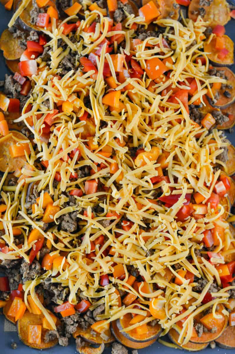 Adding cheese, veggies and ground meat to sweet potatoes.