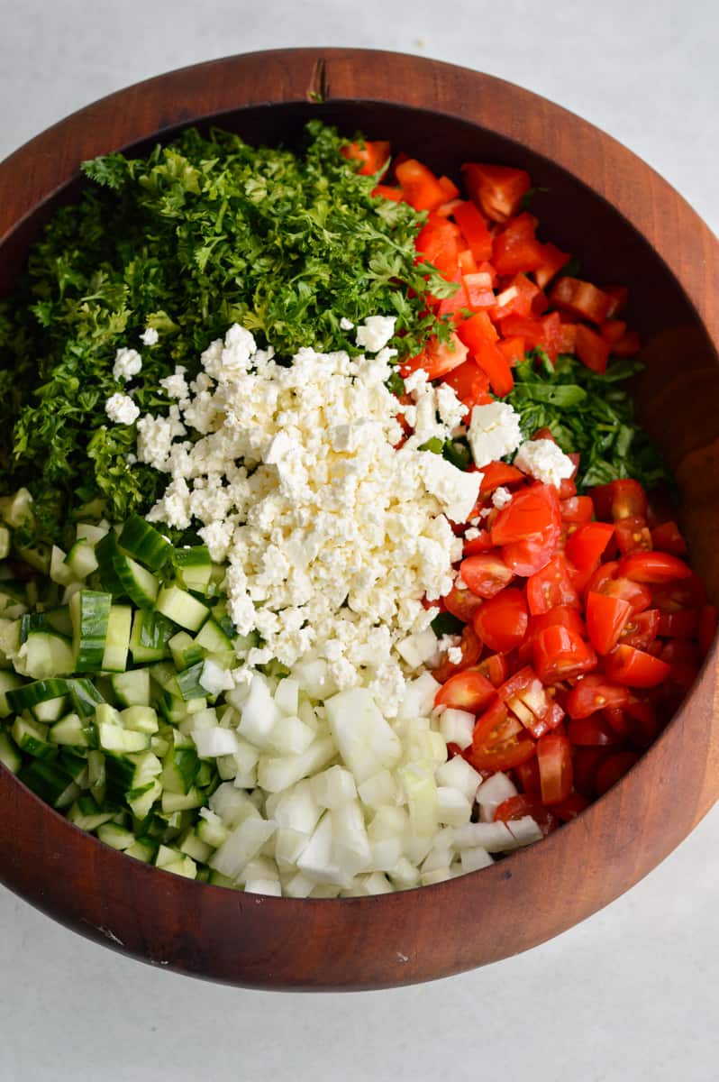 Adding feta cheese and chopped veggies to salad.