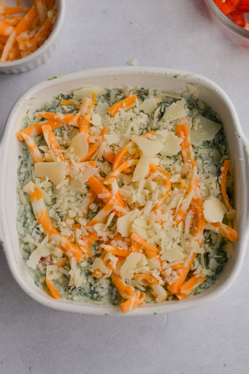 Topping spinach cottage cheese dip with shredded cheese.