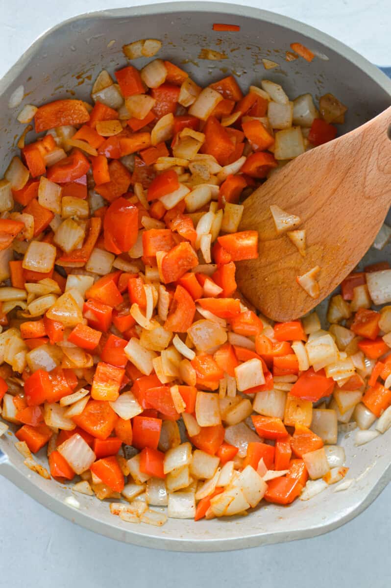 Sauteeing onions and bell peppers in a pan.