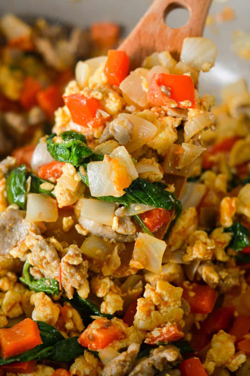 Close up of breakfast burrito filling with veggies, egg and sausage.