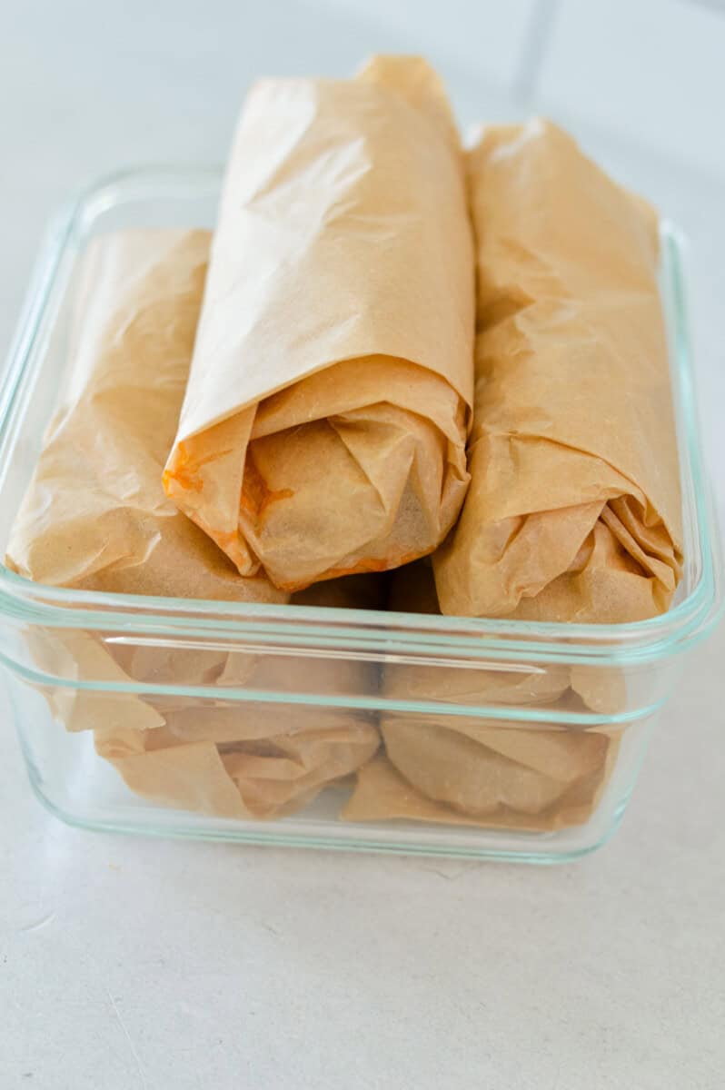 Storing breakfast burrito meal prep in glass container.
