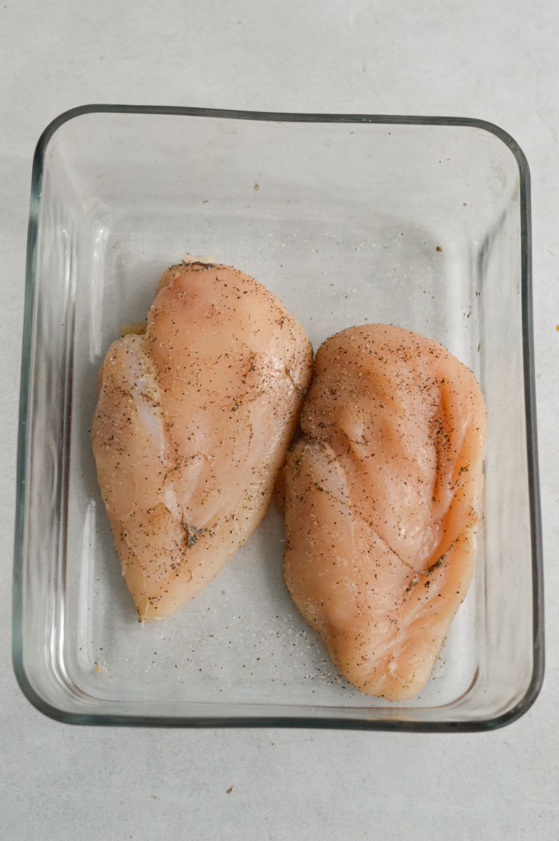 Raw chicken breast in a baking dish.