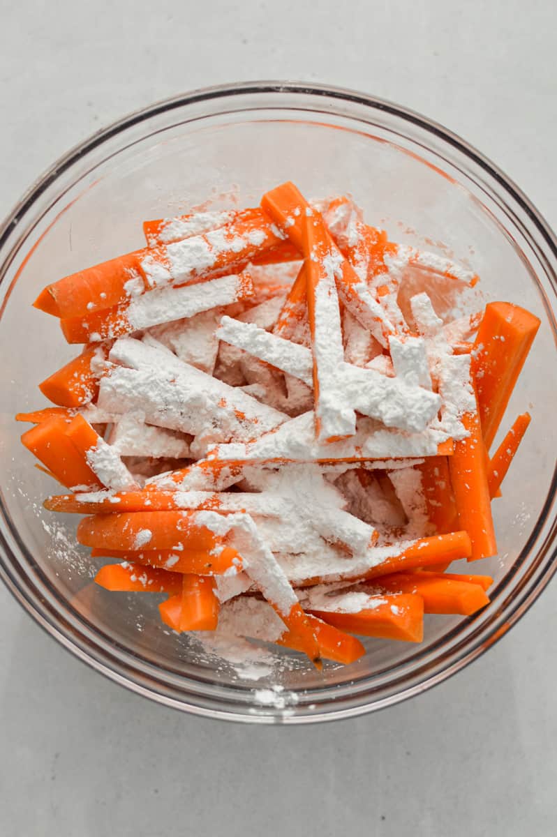 Tossing carrot sticks in spices and cornstarch.