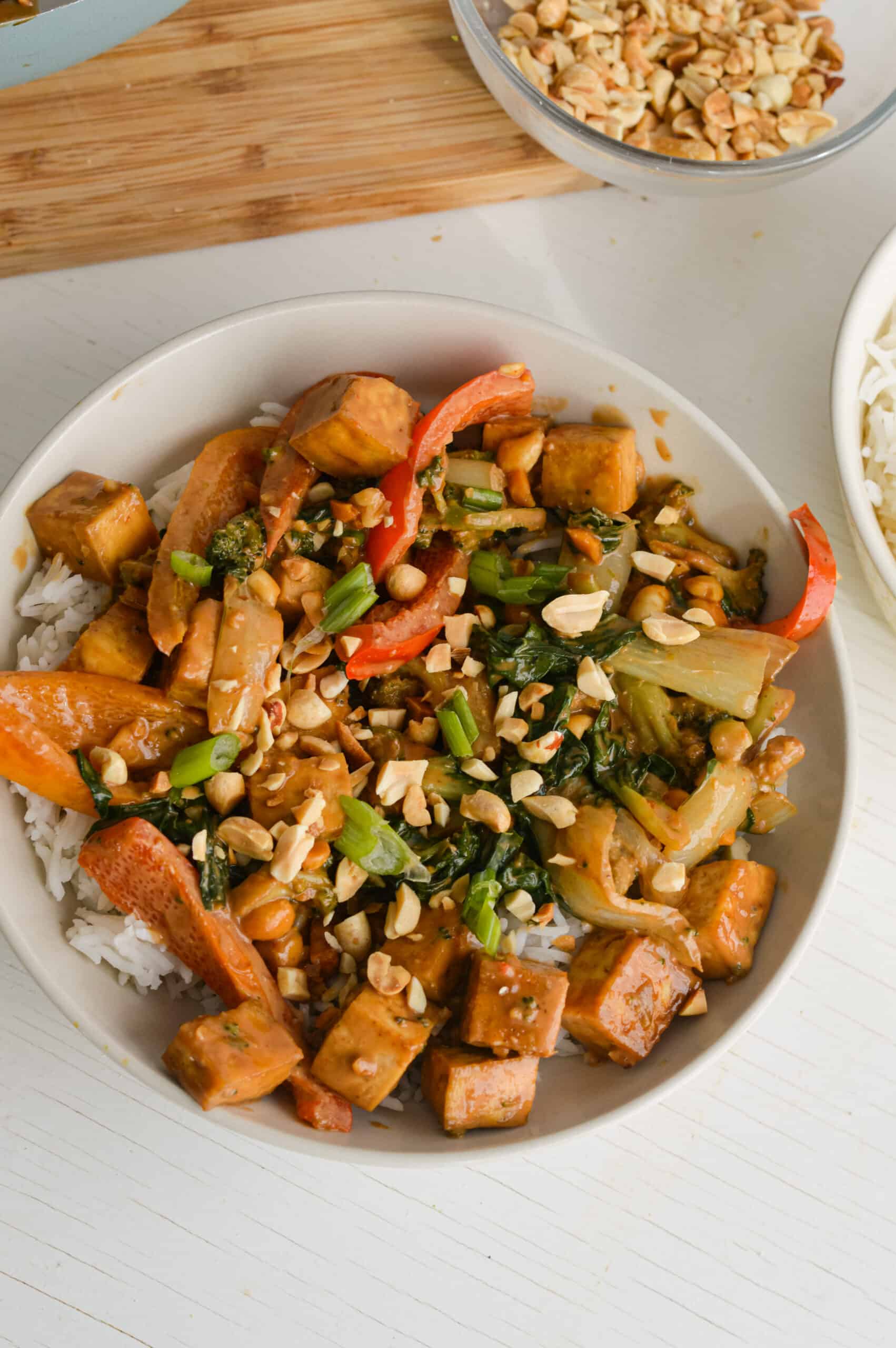 Bowl of satay tofu topped with lime slices and peanuts.