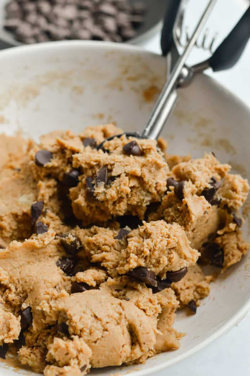Scooping vegan protein cookie dough with chocolate chunks.