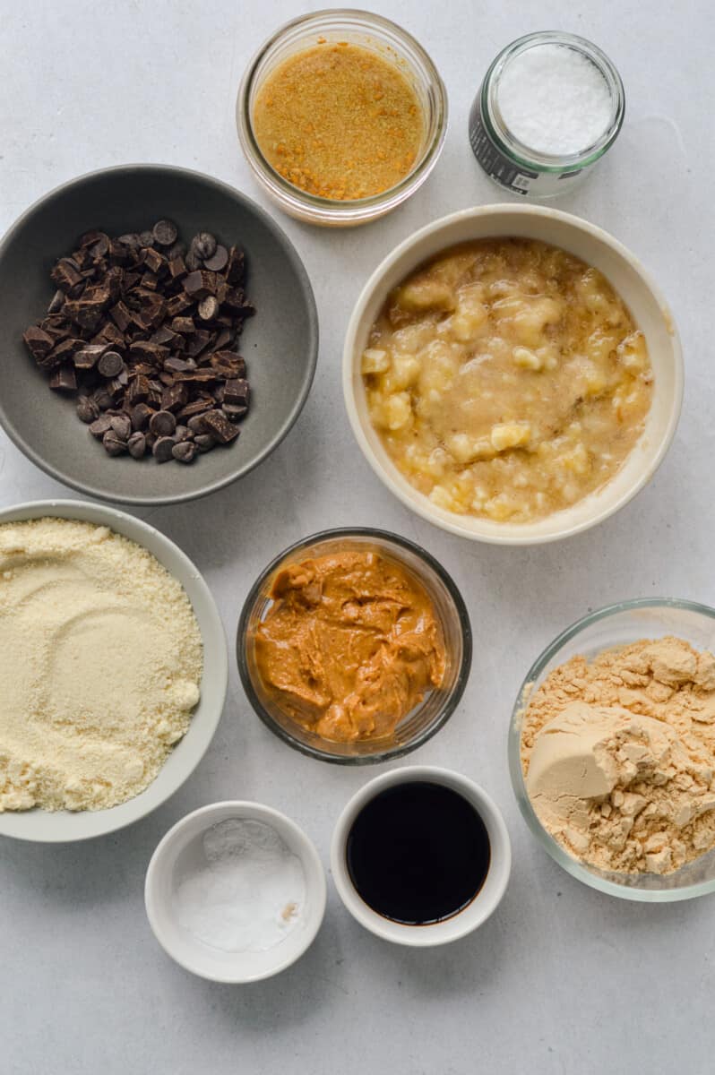 Ingredients measured including chocolate chips, protein powder, mashed banana, peanut butter, maple syrup, vanilla and flax egg.