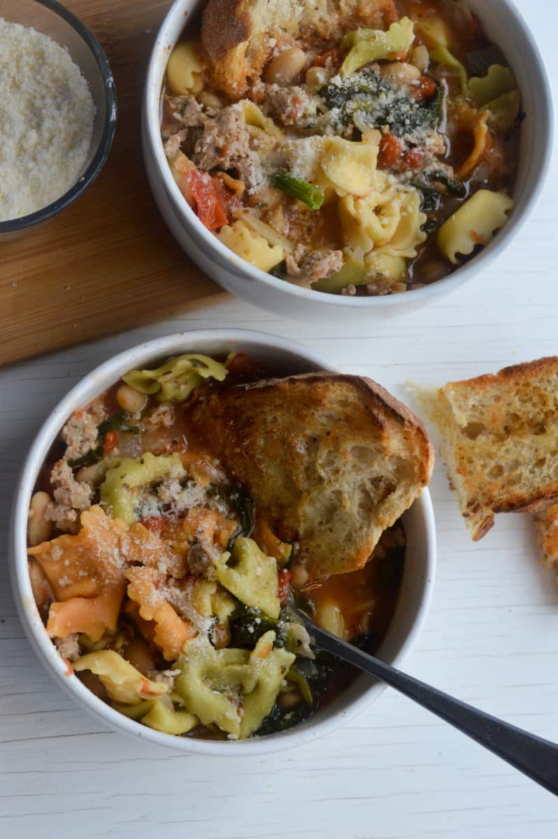 Creamy tortellini spinach soup in bowls, served with bread.