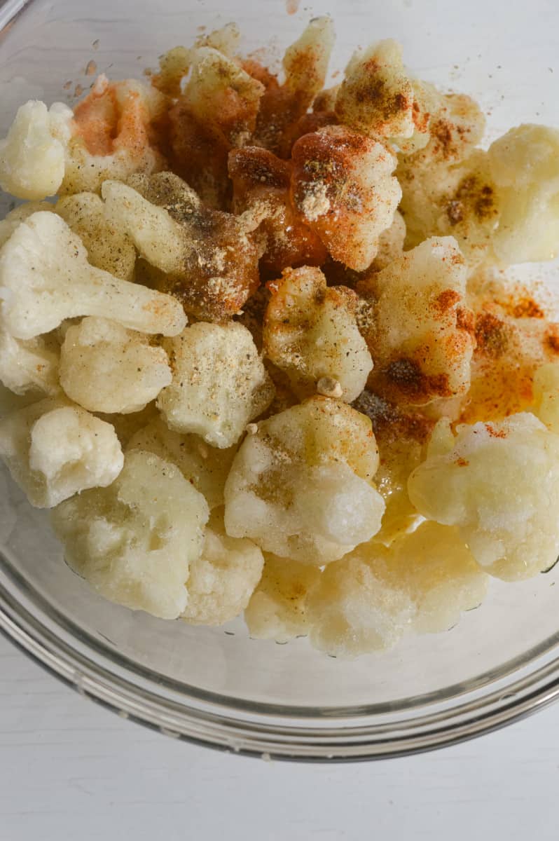 Adding spices to frozen cauliflower.