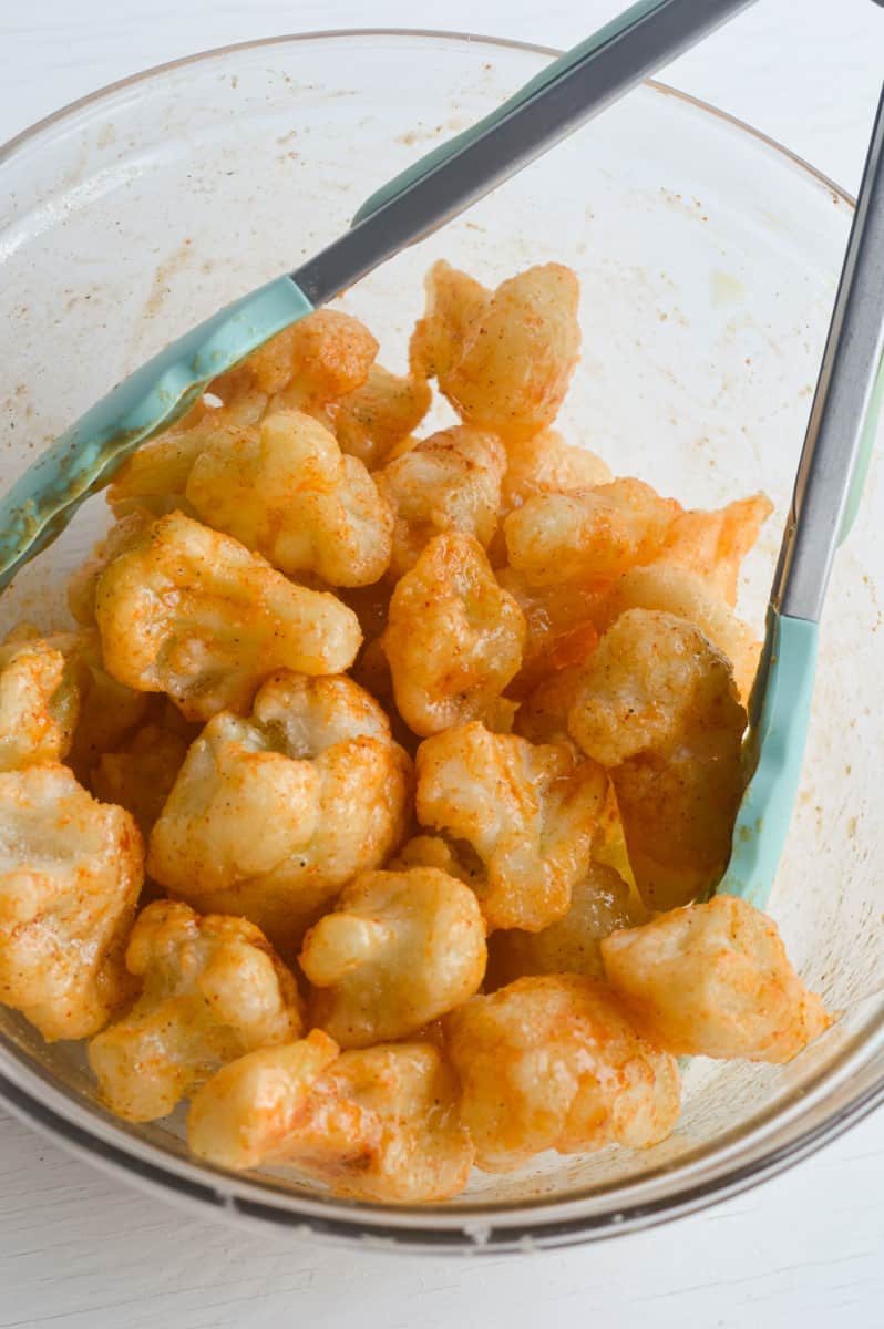 Adding hot sauce to frozen cauliflower.