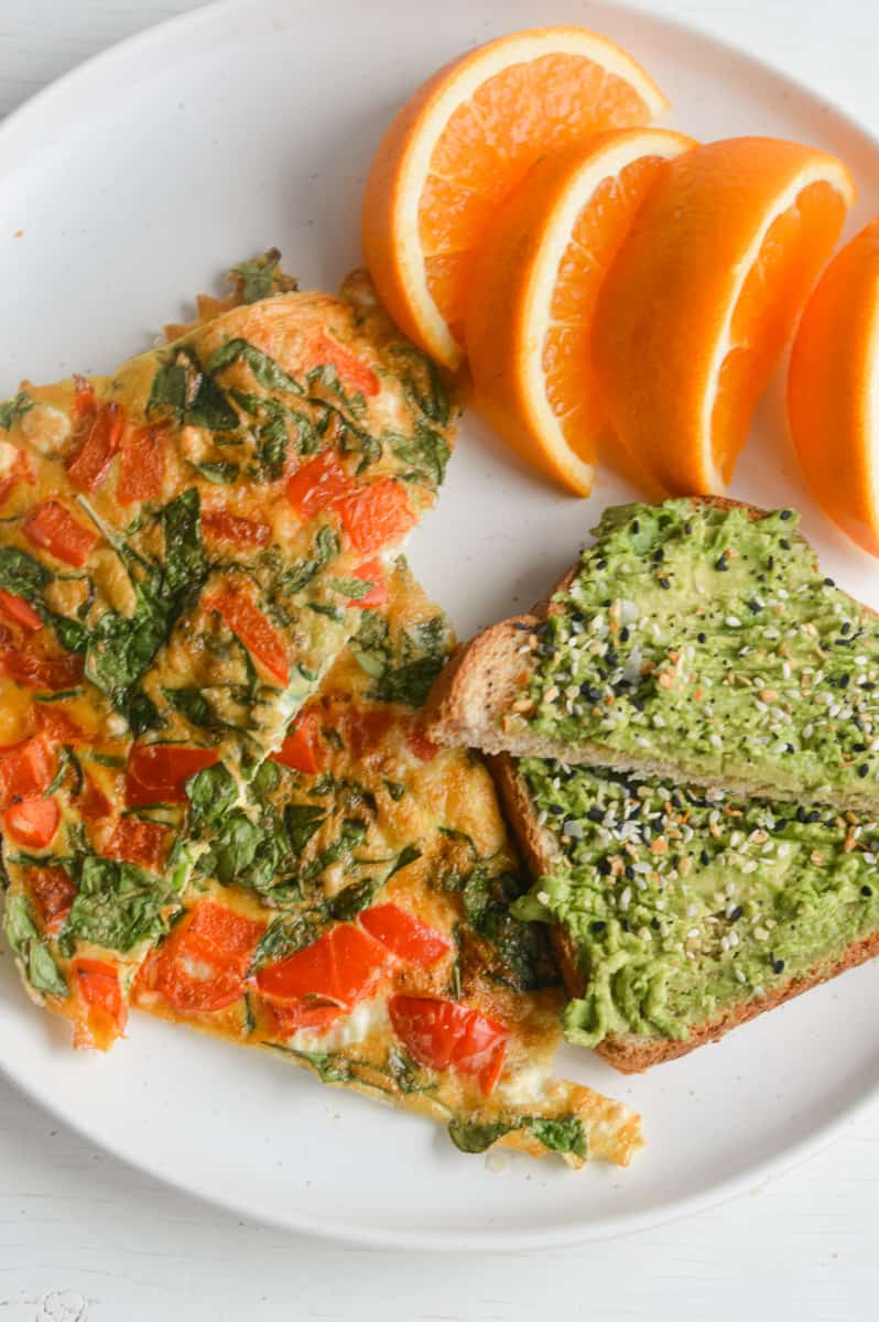 Air fryer omelette served with orange slices and avocado toast.