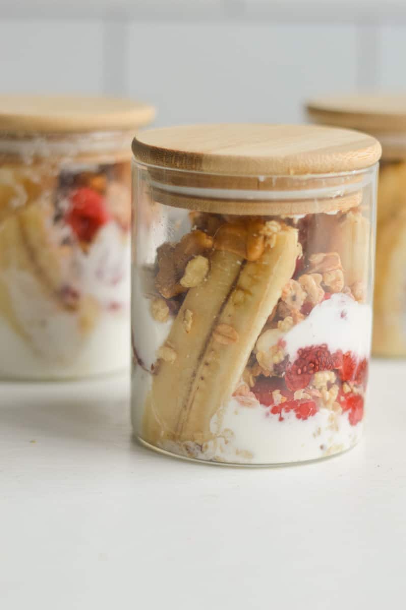 Jar of greek yogurt and granola banana splits.