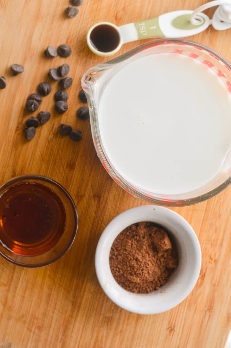 Ingredients for hot chocolate including oat milk, cocoa powder, maple syrup and vanilla.