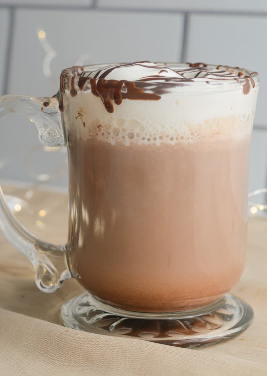 Hot chocolate topped with whipped cream and chocolate drizzle.