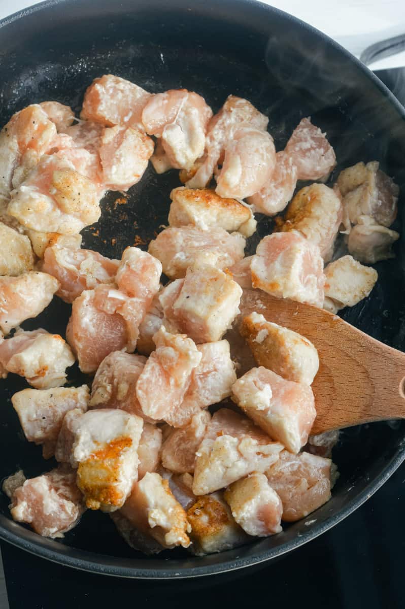 Sauteeing chicken in a pan.