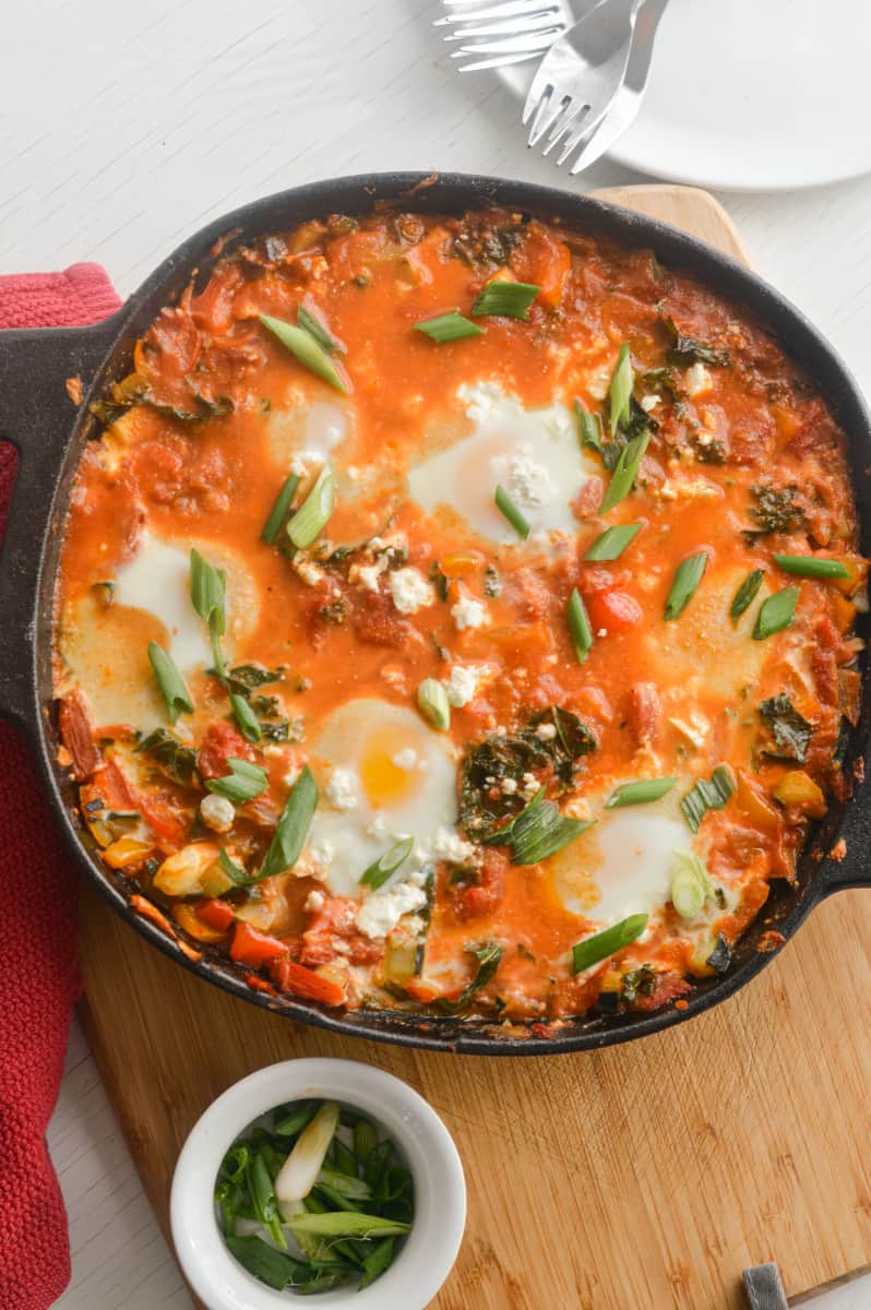 Cooking shakshuka until eggs are set.