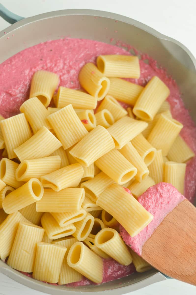 Adding pasta to pink sauce.