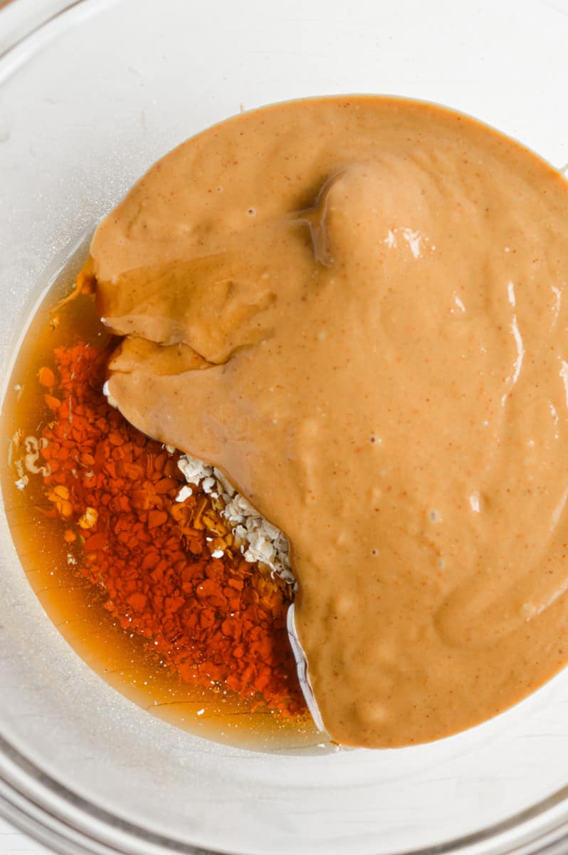 Mixing peanut butter, maple syrup and oats in a bowl.