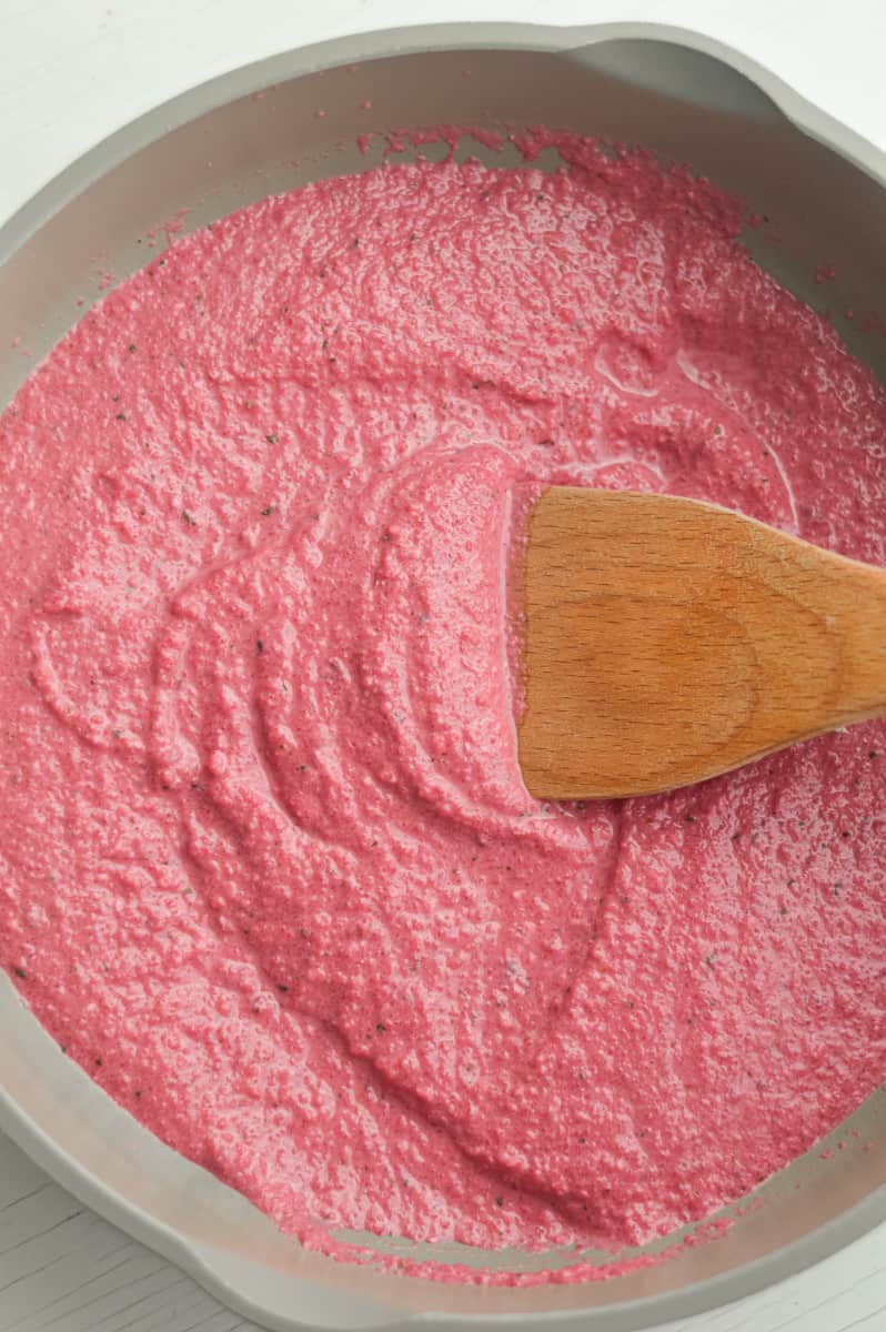 Stirring pink pasta sauce in a pan.