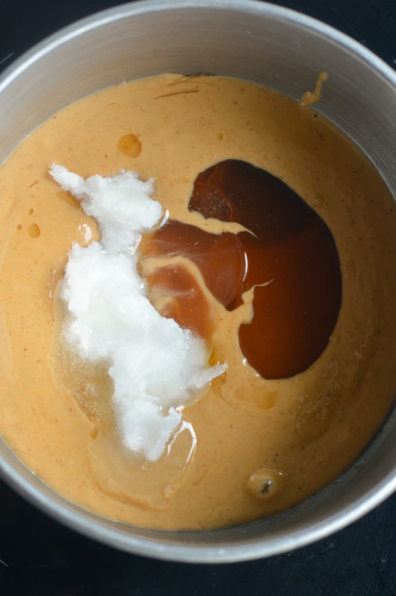 Adding peanut butter, coconut oil and maple syrup to a pot.