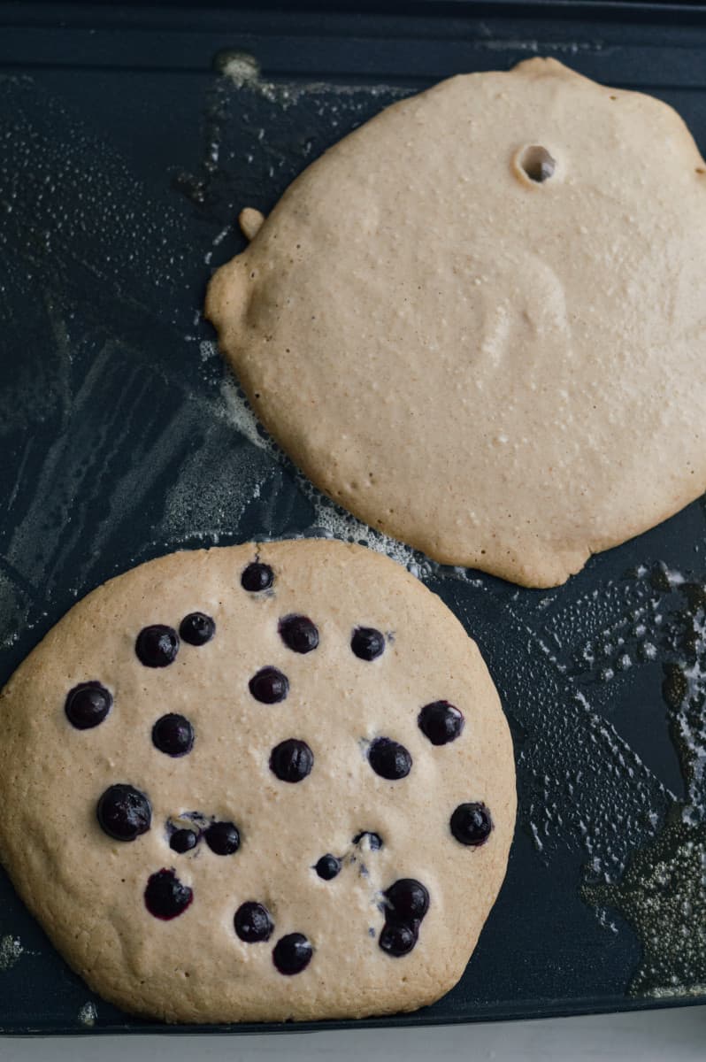 Adding blueberries to pancakes.