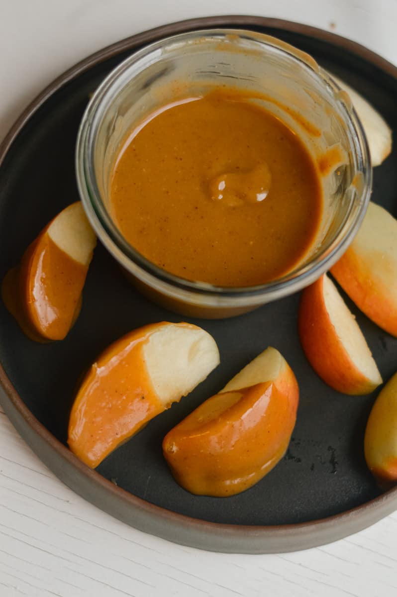Serving vegan caramel with apple slices.