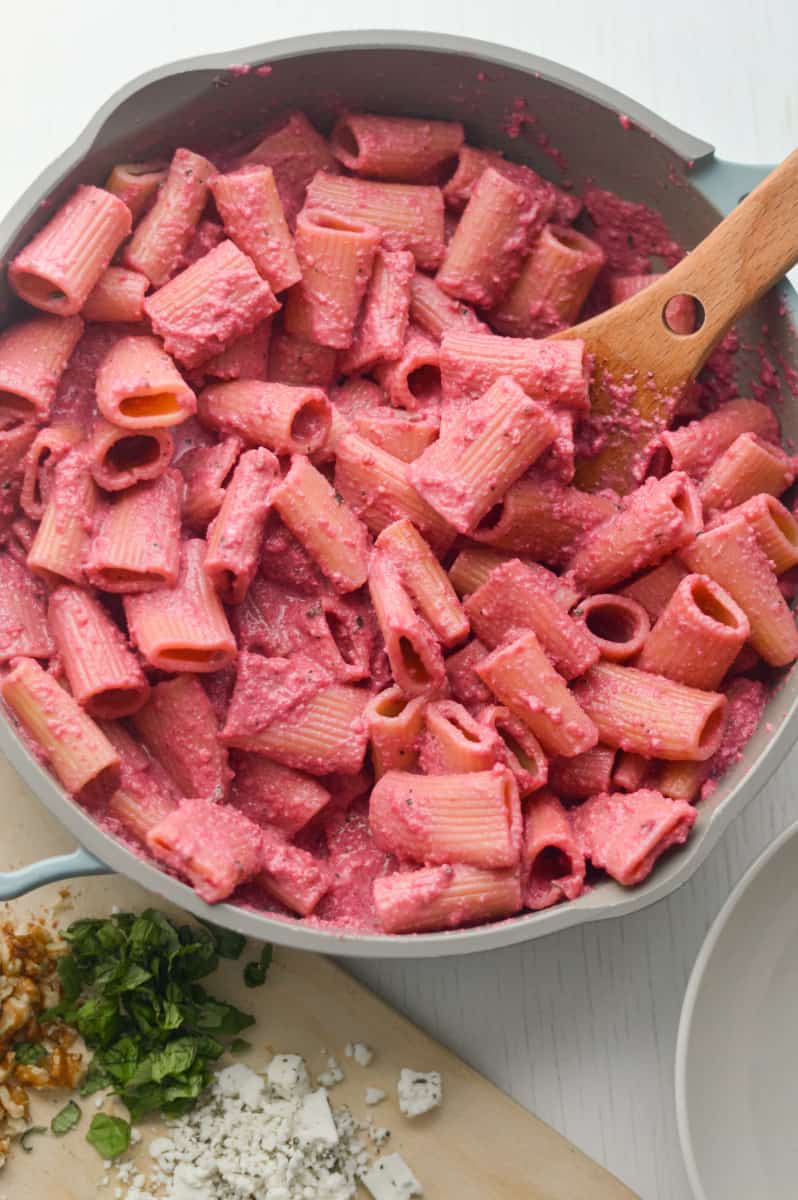 Stirring beet pasta in a pan.
