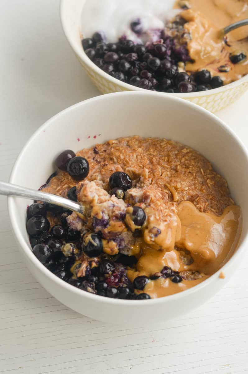 Bowls of microwave egg white oatmeal with peanut butter and blueberries.