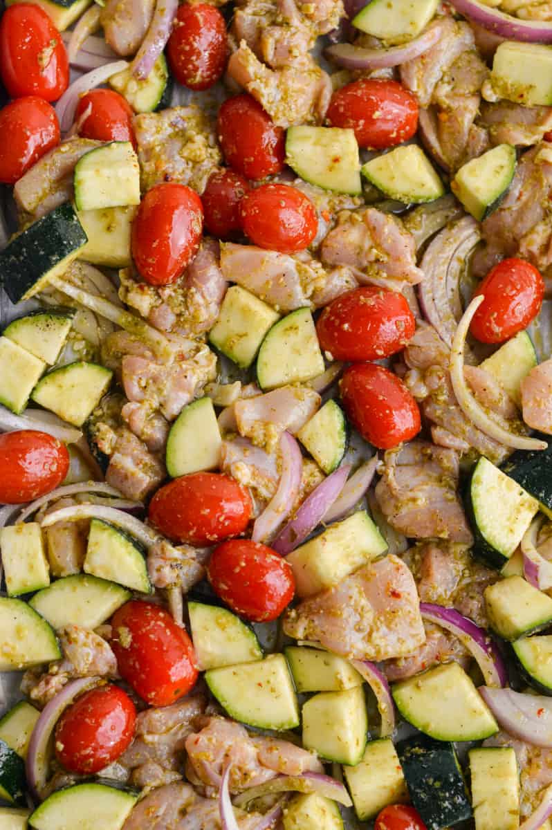 Spreading chicken and vegetables on a sheet pan.